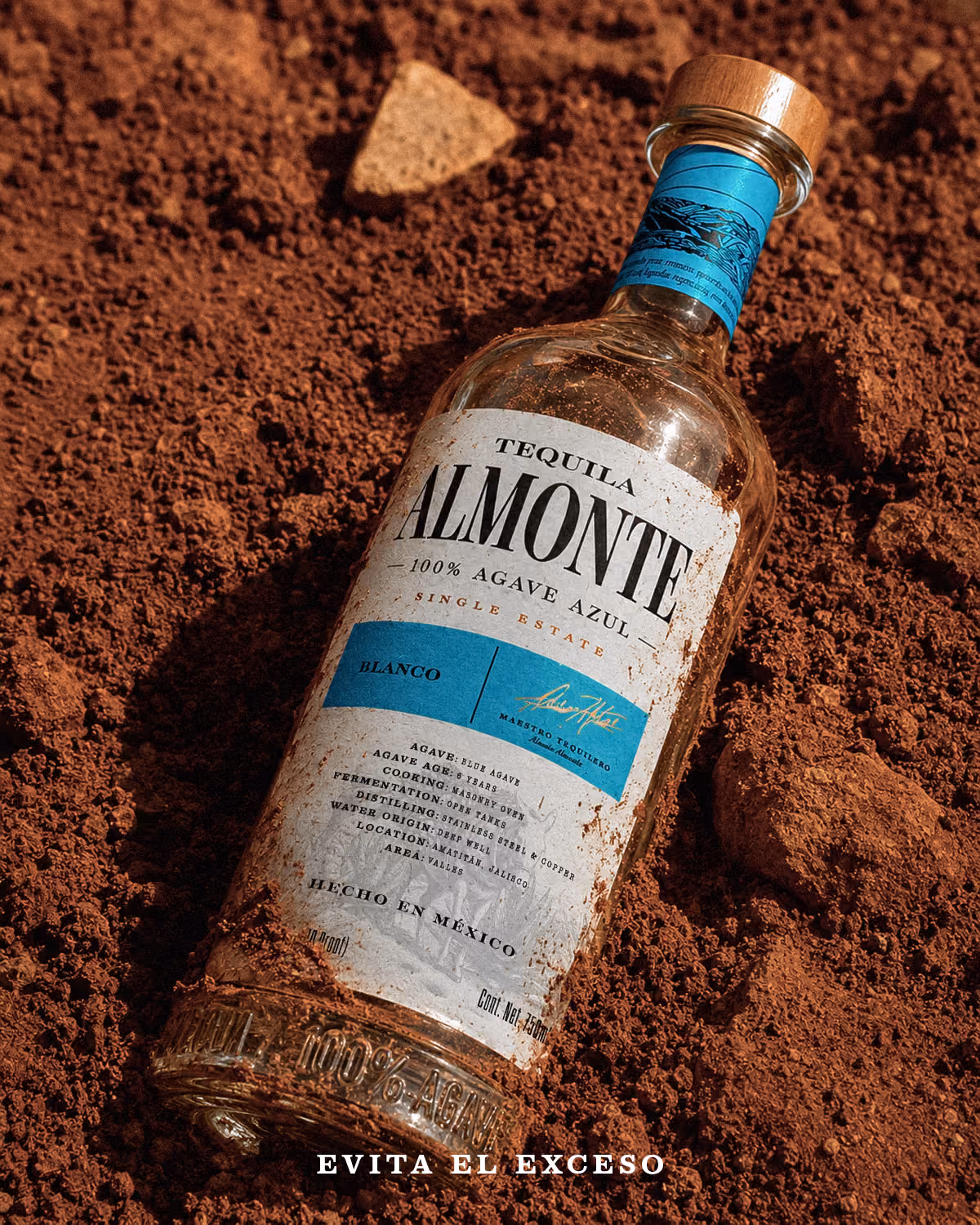 Bottle of Almonte Blanco resting on reddish soil.