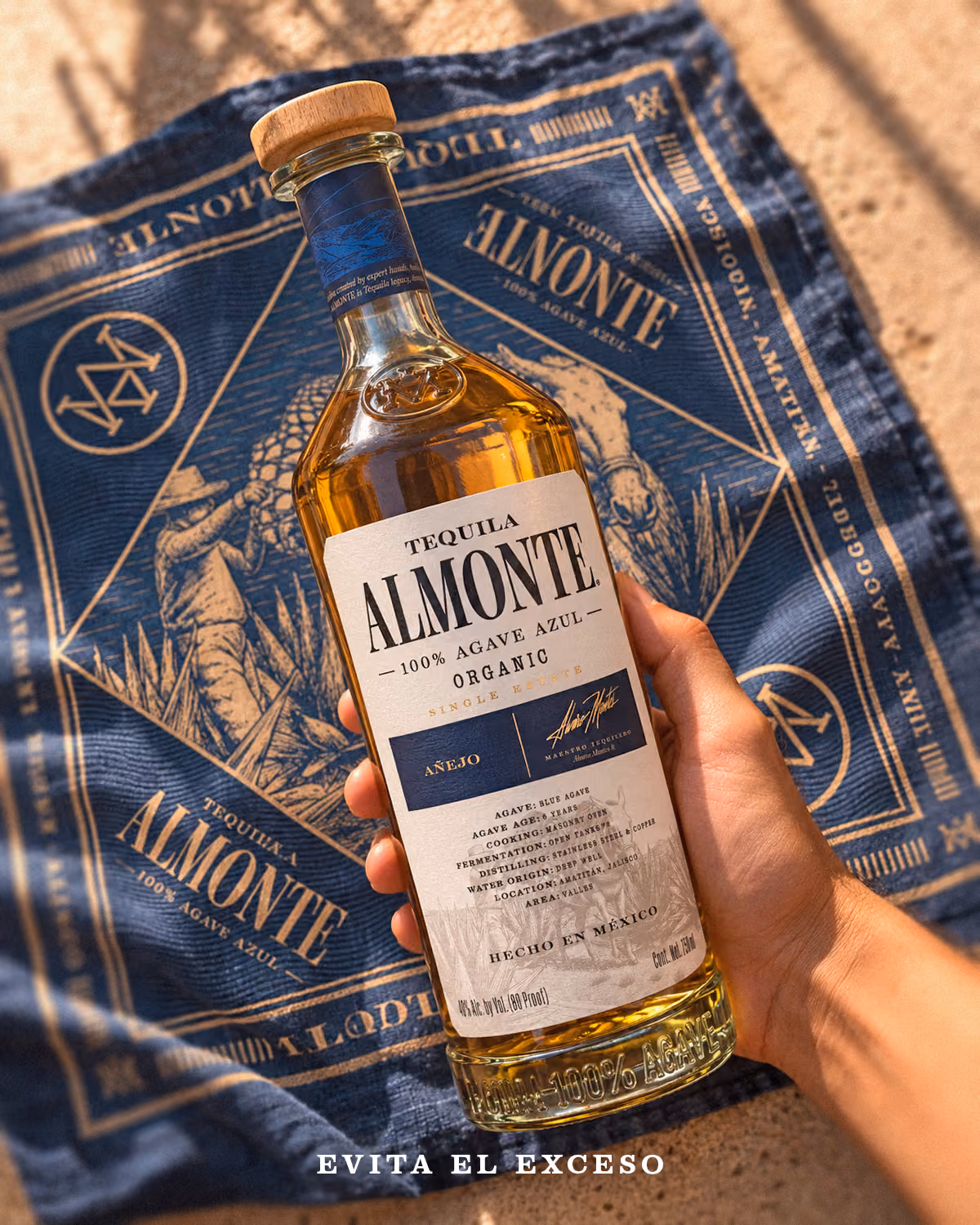 Bottle of Almonte Añejo held over a blue Almonte bandana.